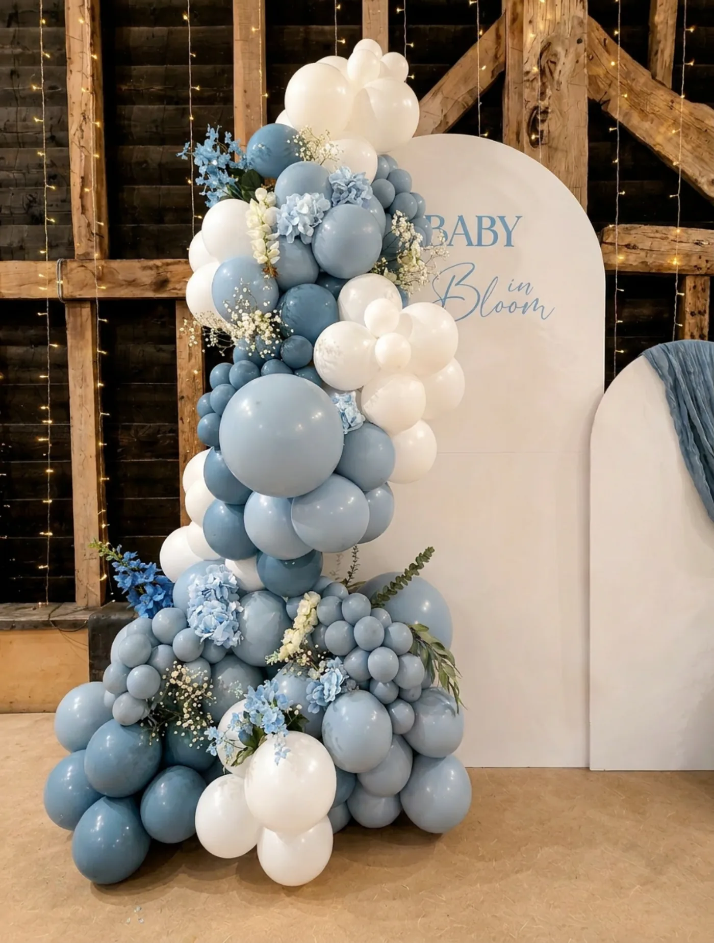 Dusty blue and white balloon arch with 'Baby in Bloom' backdrop for a Surrey baby shower by River Fox Events
