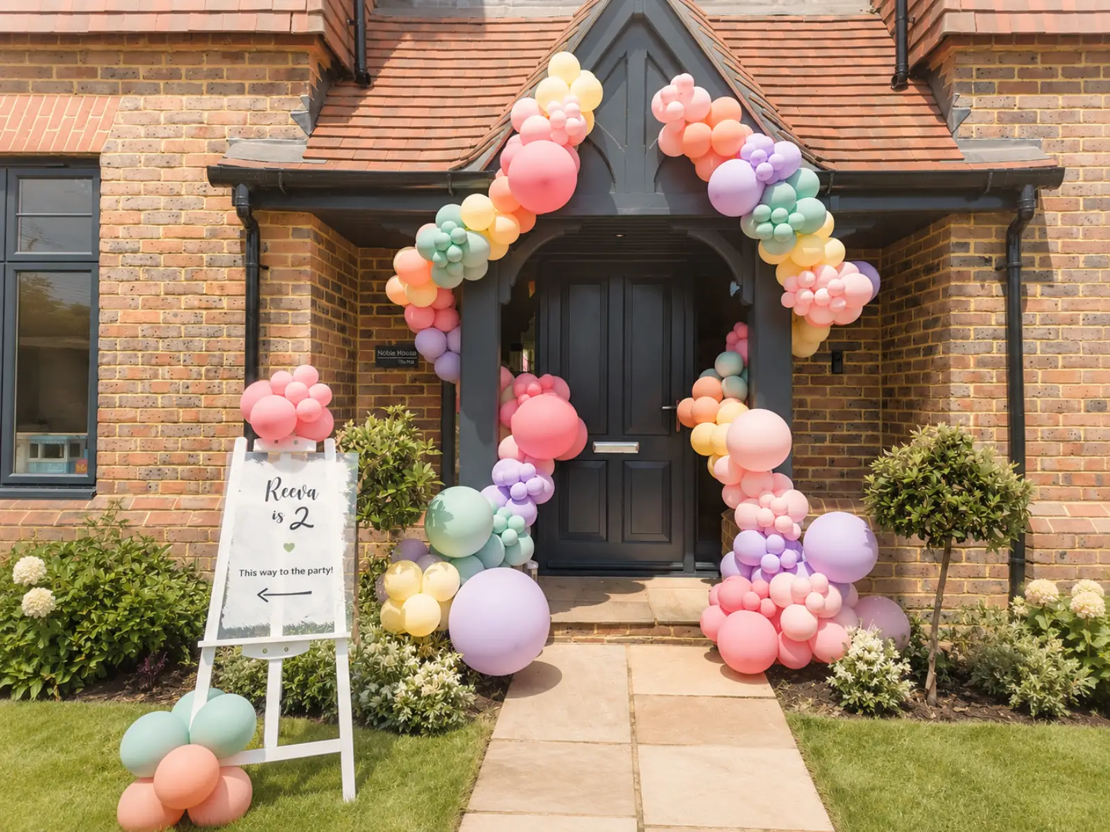 Pastel birthday entrance arch for Reeva in Surrey by River Fox Events - blush, peach and cream balloon arch over a welcome easel